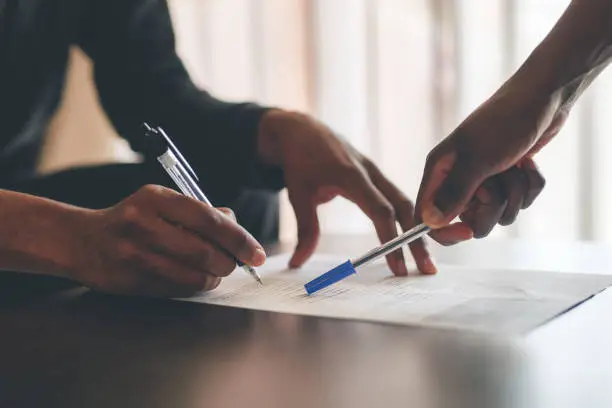 Cropped shot of an unrecognizable man filling a document with the help of a financial advisor at home