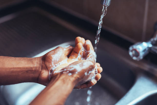 Gotta make sure germs have a zero chance Cropped shot of an unrecognizable man washing his hands in the kitchen sink at home sink photos stock pictures, royalty-free photos & images