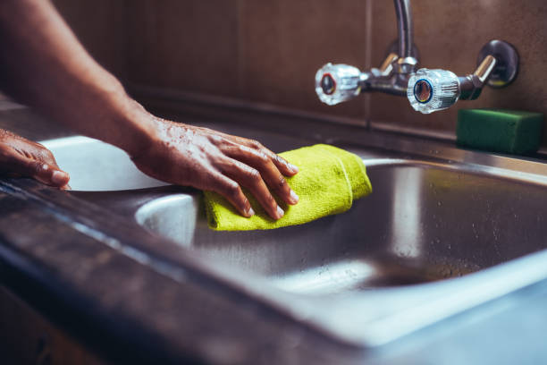 Cropped shot of an unrecognizable man wiping the kitchen sink with a cloth after washing his hands at home