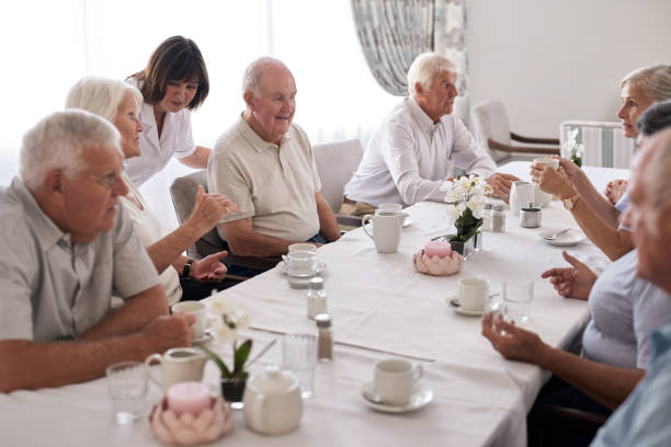 istock Smiling seniors talking with nurse around a dining table 1182622949