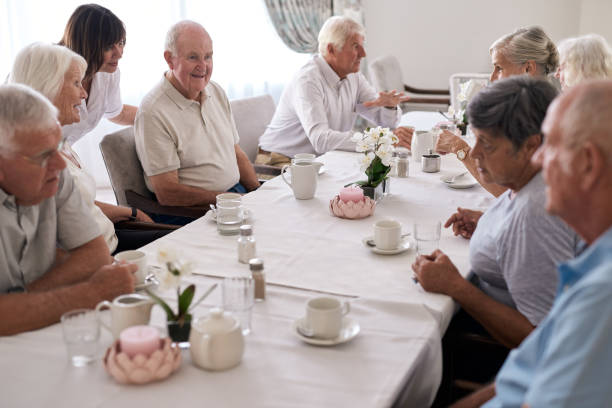 istock Smiling nurse seniors talking with seniors around a dining table 1182623078