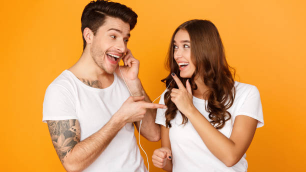 favourite song. happy couple sharing headphones, yellow background - headphones women tattoo music imagens e fotografias de stock