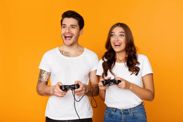 ジョイスティックでビデオゲームをプレイギャンブル興奮カップル - couple indoors studio shot horizontal ストックフォトと画像