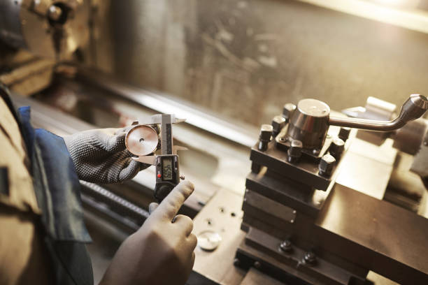 Worker making the metal details Close-up of worker wearing protective gloves measuring metal detail while working in warehouse lathe stock pictures, royalty-free photos & images