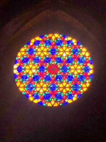 Sunlight streaming through a stained glass rose window in Palma Cathedral. Red blue yellow lead