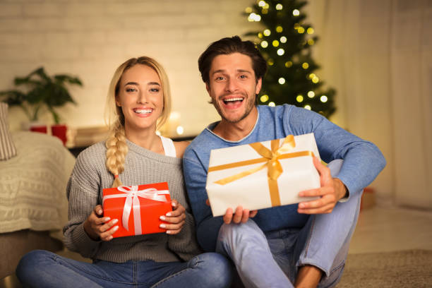 istock Millennial couple holding Christmas gift boxes and smiling 1182627592