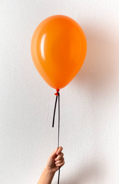 istock Woman holding orange balloon with copy space 1182628384