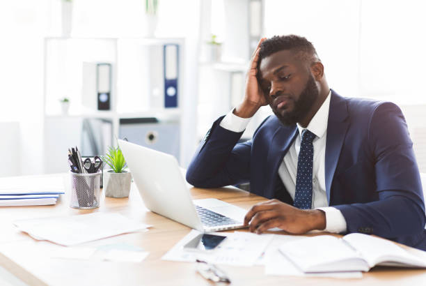 istock Exhausted young businessman working with laptop in office 1182628400