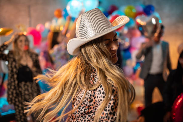 Cheerful beauty with cowboy hat dancing lively on party with friends