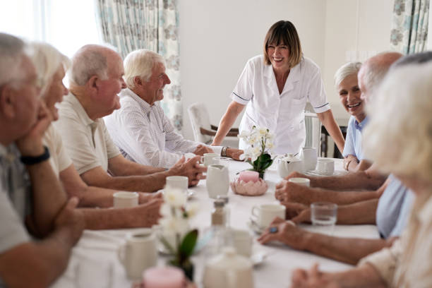 istock Smiling nurse talking with seniors around a dining room table 1182629052