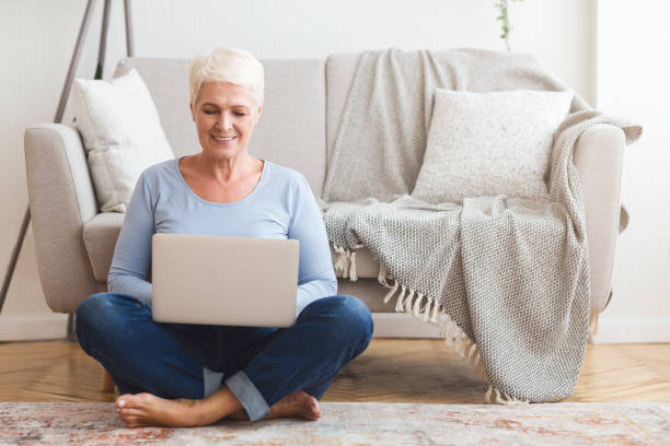 istock Resourceful mature woman sitting on floor and using laptop 1182629164