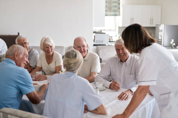 istock Smiling seniors talking with a nurse during afternoon tea together 1182629175