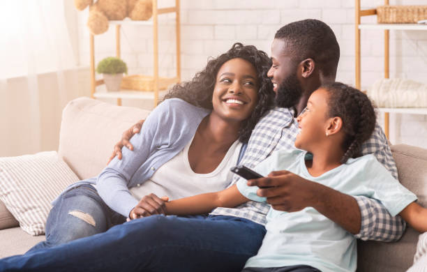 familia negra alegre divirtiéndose juntos viendo el programa de televisión - photography looking three people mother fotografías e imágenes de stock