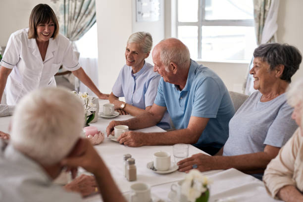 istock Smiling seniors talking to a nurse during afternoon tea 1182630375