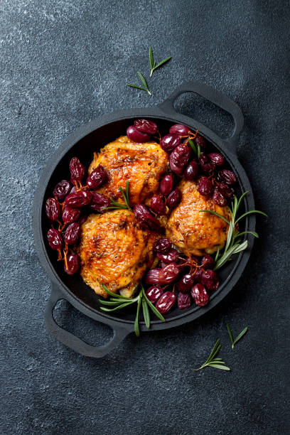 istock Roasted chicken legs with red grapes on pan over black slate stone background 1182631322