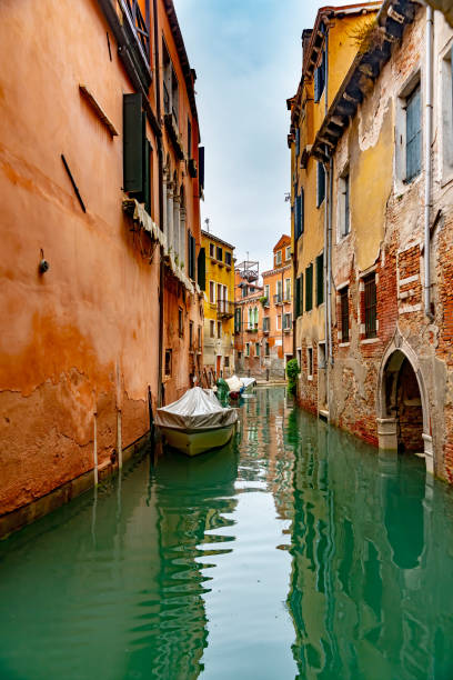 Venice canal Rio Dei Greci with moored boats and gondolas along the canalside.