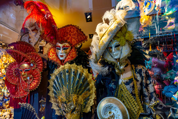 Candid image of scary and colourful masquerade masks and doll in a gift shop window in Venice .