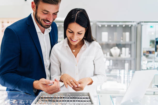 Attractive middle age couple in jewelry store Beautiful couple enjoying in shopping at modern jewelry store. Young woman try it out gorgeous necklace and ring. ring jewelry stock pictures, royalty-free photos & images