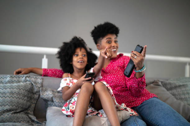 istock Sister watching TV and pointing at it 1182639696