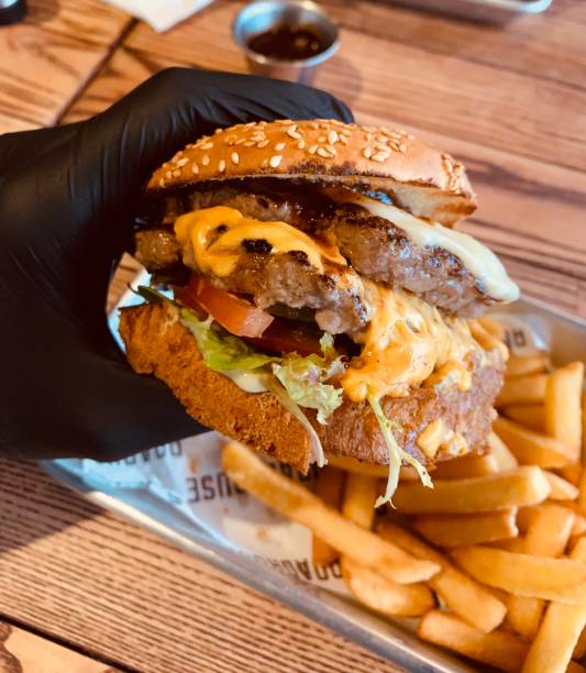 istock juicy burger in a gloved hand 1182640489