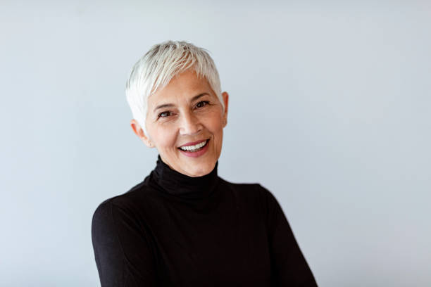 Live your life and forget your age Casual portrait of happy mature woman with natural white short hair and minimal makeup. standing against gray wall. shorthair stock pictures, royalty-free photos & images