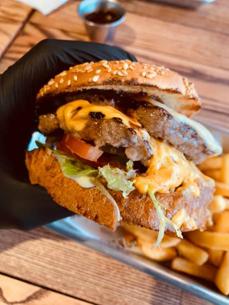 istock juicy burger in a gloved hand 1182640693