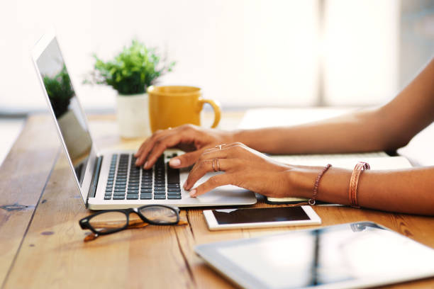 I love working from home Cropped shot of an unrecognizable businesswoman sitting alone and typing on her laptop during the day at home notebook stock pictures, royalty-free photos & images