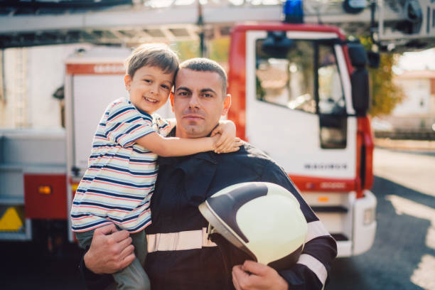 손에 어린 소년을 들고 소방관의 초상화 - fire department heroes portrait occupation 뉴스 사진 이미지