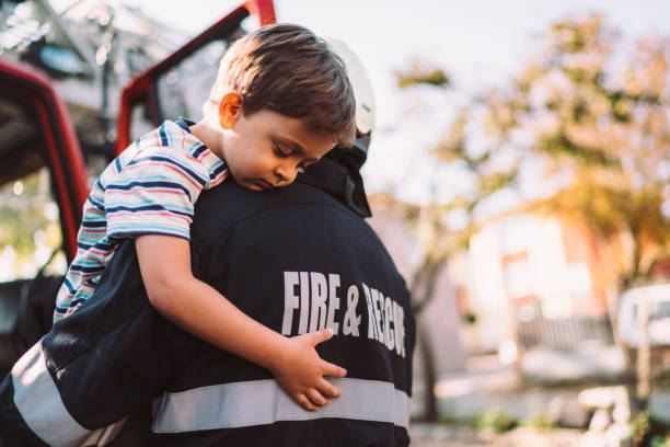 Firefighter rescue operation Firefighter carrying little boy after successful rescue operation fire station stock pictures, royalty-free photos & images