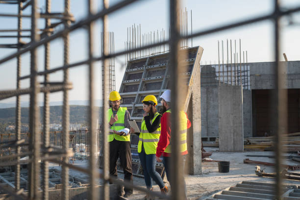 os trabalhadores da construção discutem as plantas do edifício. - safety meeting construction site construction - fotografias e filmes do acervo