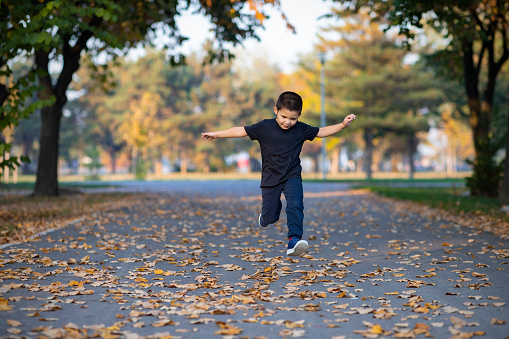 Carefree kids having fun while running away from their parents in autumn day at the park.