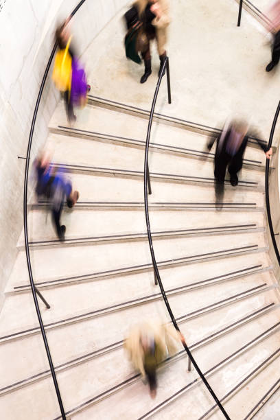 istock Blurred Motion of People on Spiral Staircase 1182642409
