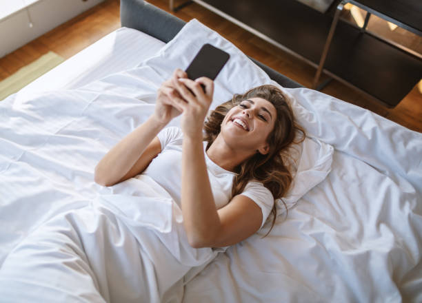 istock Young woman using a mobile phone in bed 1182643128