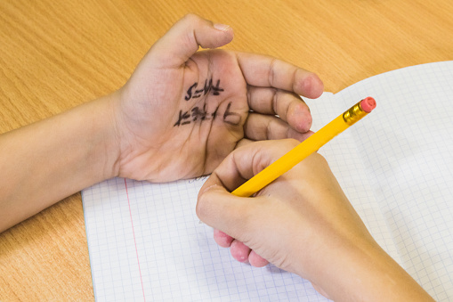 Student writes off the test from the cheat sheet written on the hand.