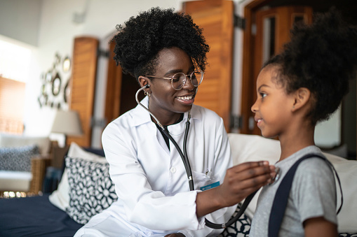 Home caregiver examining young girl