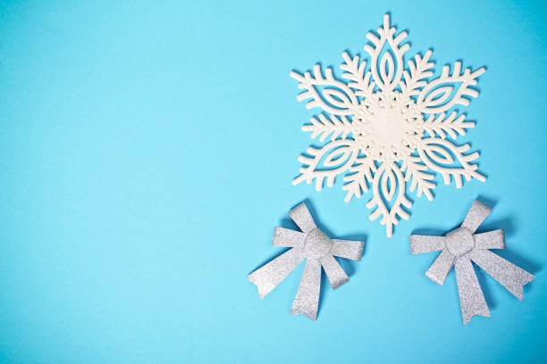 istock White glittery snowflake and bows on pastel blue background 1182646377