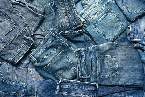 Textured background with variety of mens and womens blue jeans. Top view.