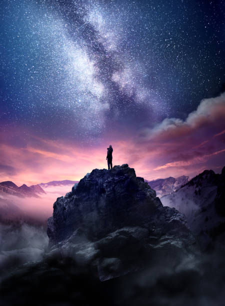 Wonders Of The Night Sky Night sky long exposure landscape. A man standing on a high rock watching the stars rise into the night sky. Photo composite. staring stock pictures, royalty-free photos & images