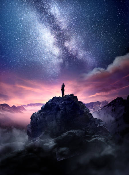 Wonders Of The Night Sky Night sky long exposure landscape. A man standing on a high rock watching the stars rise into the night sky. Photo composite. awe stock pictures, royalty-free photos & images