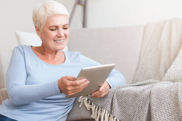 istock Happy old woman using digital tablet at home 1182647831