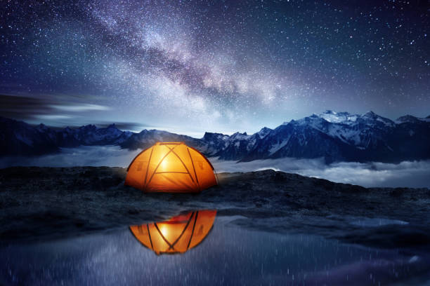 Camping Adventure Under The Stars Camping adventure in the mountains. A tent pitched up and glowing under the milky way. Photo composite. extreme terrain stock pictures, royalty-free photos & images