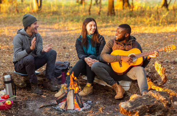 istock Happy hikers sitting around campfire and singing 1182648243