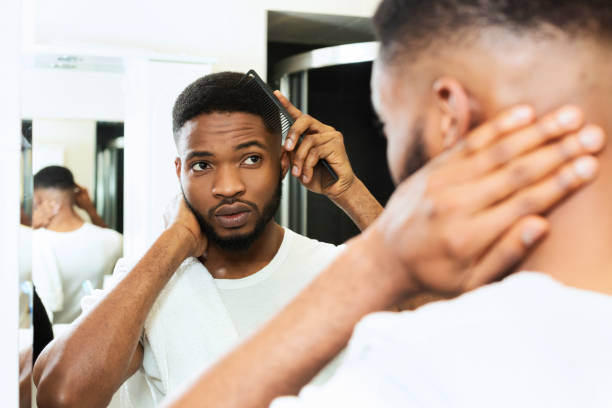 istock Young african man combing his hair in bathroom 1182648893