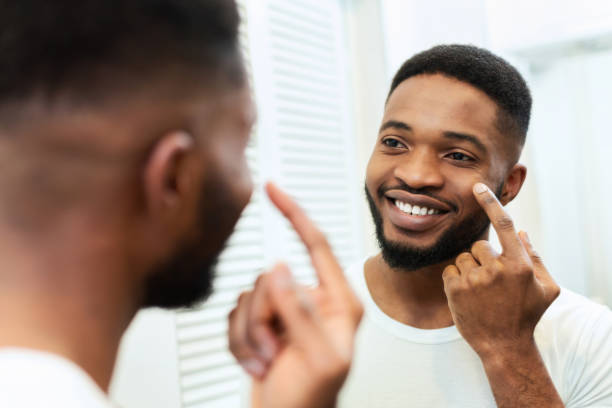 istock Cheerful black man applying pampering cream on face in bathroom 1182648942