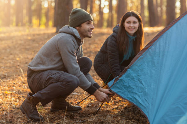 istock Active couple settle camping tent in the middle of forest 1182649103