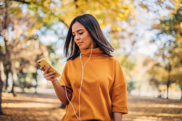 istock Beautiful young woman using phone in park 1182649287