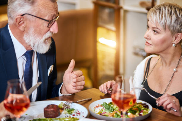 istock Pretty lady and elderly man having friendly conversation in restaurant 1182649566