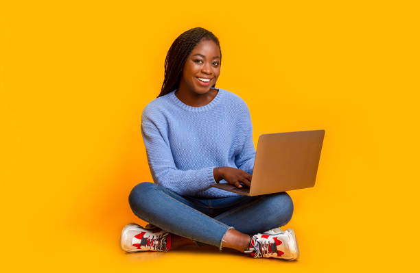 istock Smiling young lady chatting online over yellow studio background 1182650769