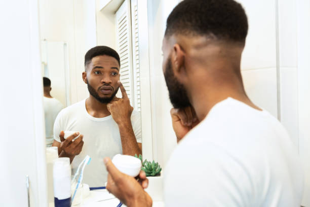 istock Handsome african man applying moisturizing cream in bathroom 1182651191