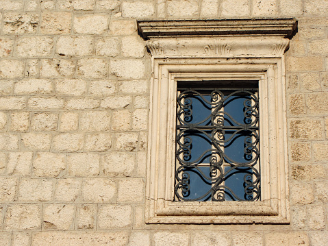 Decorative window on an old historical stone building in a Mediterranean old town.